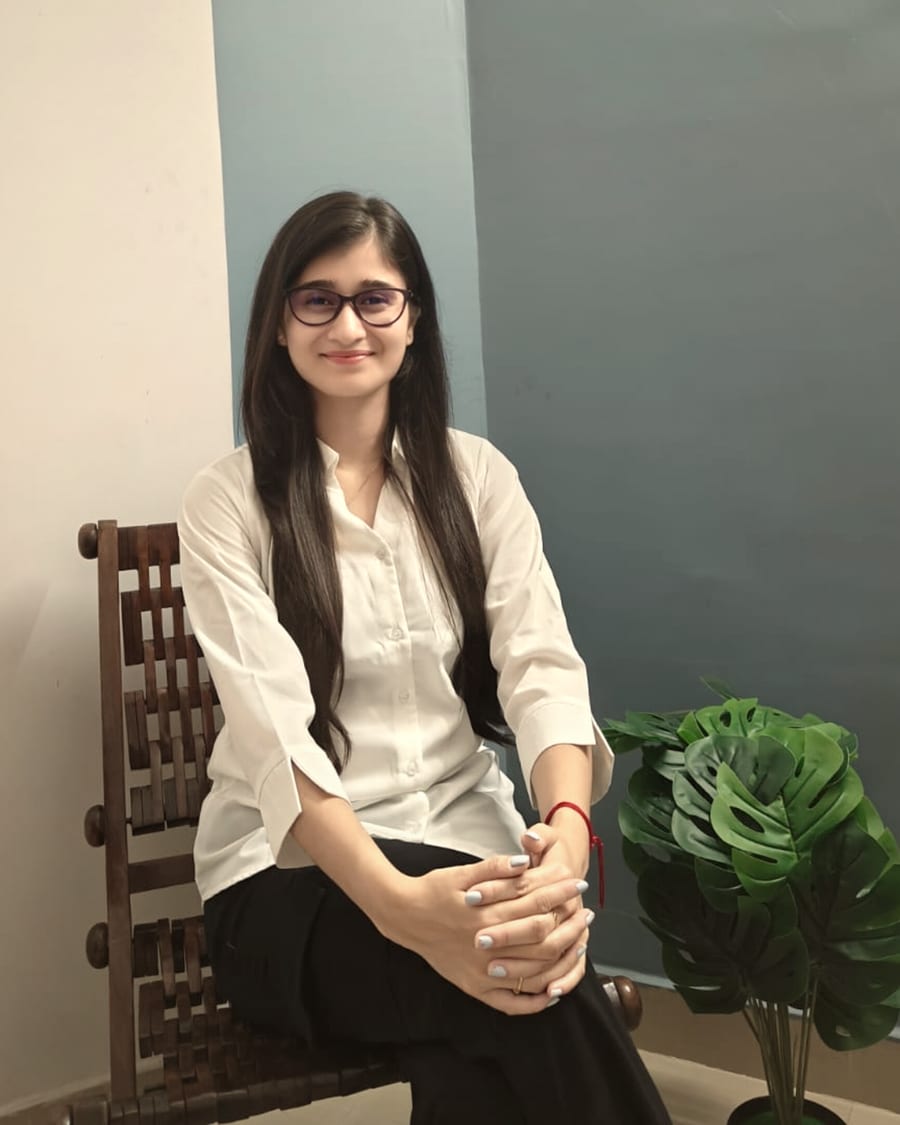 Antara Bezbarua, counselling psychologist, seated in a wooden chair beside a plant